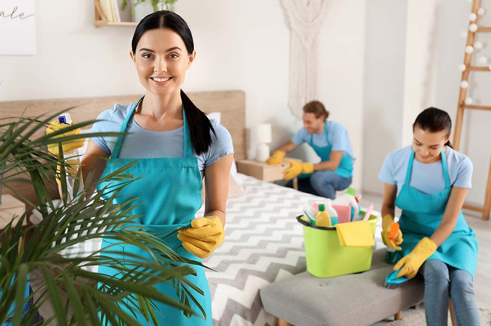 three cleaners working together to clean a bedroom