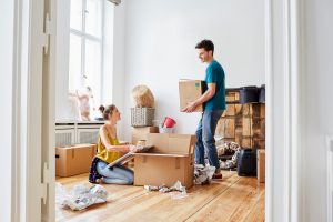 Young man and woman unpacking cardboard boxes at new apartment