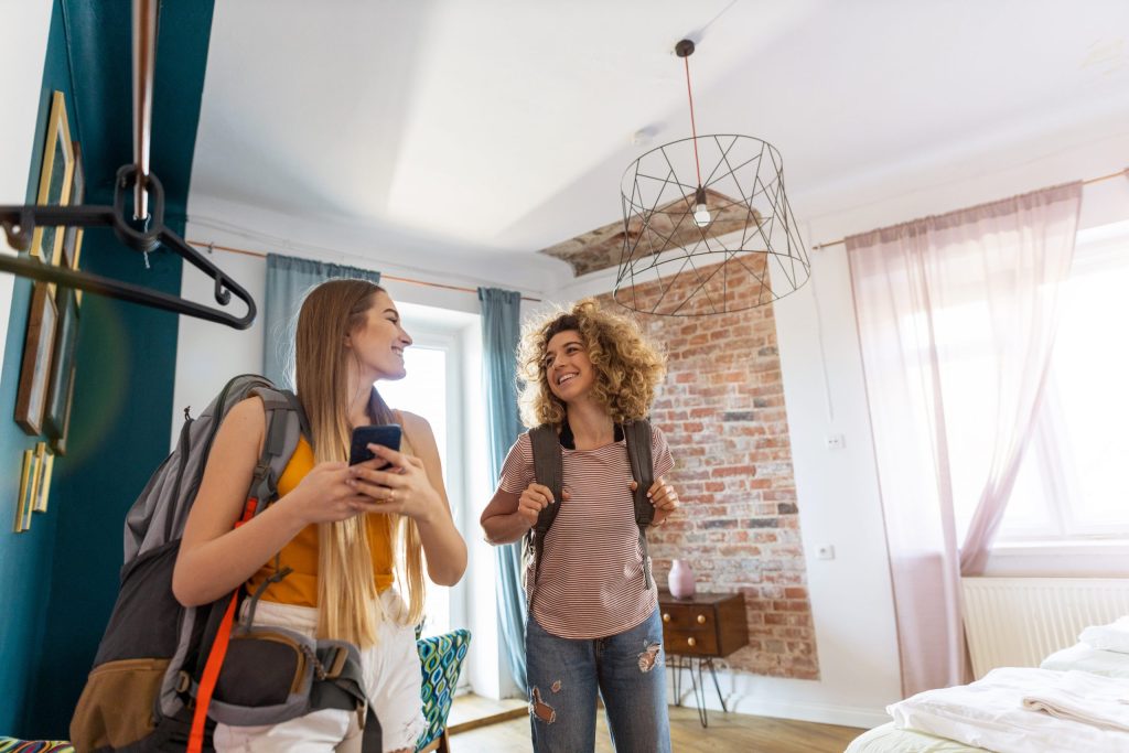 Two guests with backpacks arriving at a bright, freshly cleaned rental